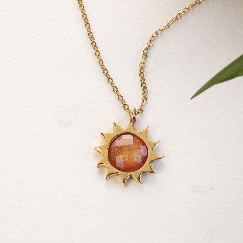 Sun necklace with orange stone, handmade brass pendant plated in 24k gold on a stainless steel chain. Vibrant celestial-inspired artisan jewelry, elegant handmade accessory, affordable wearable art by Sunny Designs small business. Κολιέ Sun με πορτοκαλί πέτρα, χειροποίητο μενταγιόν από ορείχαλκο επιχρυσωμένο 24 καράτια σε ατσάλινη αλυσίδα. Ζωντανό κόσμημα εμπνευσμένο από τα ουράνια σύμβολα, κομψό χειροποίητο αξεσουάρ, προσιτή φορετή τέχνη από τη μικρή επιχείρηση Sunny Designs.