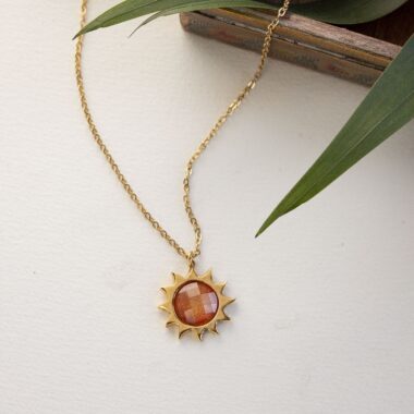 Sun necklace with orange stone, handmade brass pendant plated in 24k gold on a stainless steel chain. Vibrant celestial-inspired artisan jewelry, elegant handmade accessory, affordable wearable art by Sunny Designs small business. Κολιέ Sun με πορτοκαλί πέτρα, χειροποίητο μενταγιόν από ορείχαλκο επιχρυσωμένο 24 καράτια σε ατσάλινη αλυσίδα. Ζωντανό κόσμημα εμπνευσμένο από τα ουράνια σύμβολα, κομψό χειροποίητο αξεσουάρ, προσιτή φορετή τέχνη από τη μικρή επιχείρηση Sunny Designs.