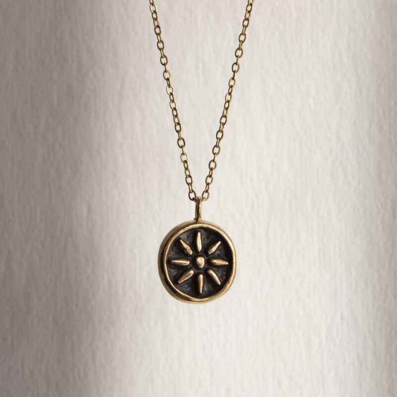 Kid of the Sun necklace with stainless steel chain and handmade brass sun pendant with patina finish. Unique artisan jewelry inspired by celestial symbols, bohemian wearable art, affordable handmade accessory by Sunny Designs small business.Κολιέ Kid of the Sun με ατσάλινη αλυσίδα και χειροποίητο μενταγιόν ήλιου από ορείχαλκο με πατίνα. Μοναδικό χειροποίητο κόσμημα εμπνευσμένο από τα ουράνια σύμβολα, μποέμ φορετή τέχνη, προσιτό αξεσουάρ από τη μικρή επιχείρηση Sunny Designs.