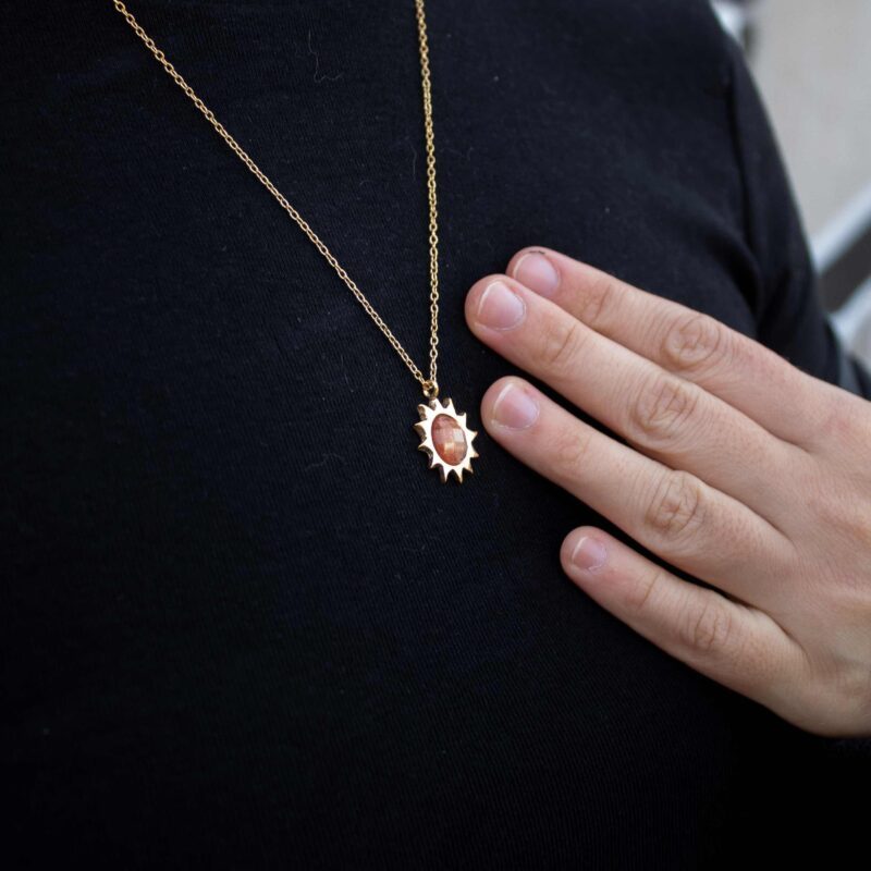 Sun necklace with orange stone, handmade brass pendant plated in 24k gold on a stainless steel chain. Vibrant celestial-inspired artisan jewelry, elegant handmade accessory, affordable wearable art by Sunny Designs small business. Κολιέ Sun με πορτοκαλί πέτρα, χειροποίητο μενταγιόν από ορείχαλκο επιχρυσωμένο 24 καράτια σε ατσάλινη αλυσίδα. Ζωντανό κόσμημα εμπνευσμένο από τα ουράνια σύμβολα, κομψό χειροποίητο αξεσουάρ, προσιτή φορετή τέχνη από τη μικρή επιχείρηση Sunny Designs.