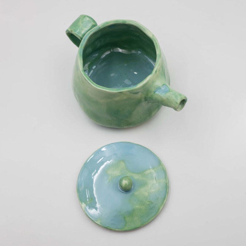 An artisan-crafted ceramic teapot, skillfully formed and glazed by hand. Its smooth surface showcases intricate textures and delicate patterns, reflecting the artisan's meticulous craftsmanship. The teapot's graceful curves and elegant spout evoke a sense of timeless beauty and functionality, inviting contemplation and appreciation of its artisanal quality.