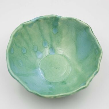 A close-up image of a green ceramic glazed handmade bowl . The bowl exhibits a smooth texture with intricate details, showcasing its artisanal craftsmanship and glossy finish." Κοντινή εικόνα ενός πράσινου κεραμικού γυαλισμένου χειροποίητου μπολ. Το μπολ εμφανίζει μια ομαλή υφή με λεπτομερείς λεπτομέρειες, επιδεικνύοντας τη χειροτεχνία του τεχνίτη και το γυαλιστερό τελείωμά του.