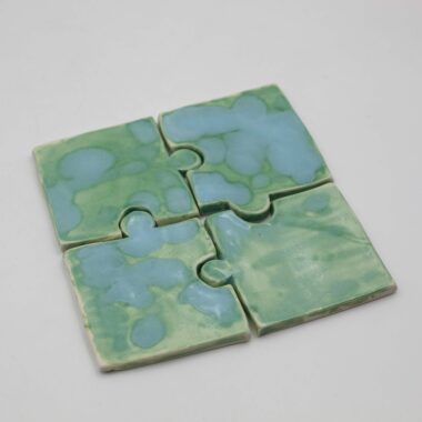 A set of ceramic glazed coasters arranged neatly on a tabletop. Each coaster features a glossy finish with vibrant colors, adding a pop of charm to any surface. The glazed surface ensures protection against moisture and heat, making them both decorative and functional accessories for any home.