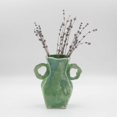 handmade ceramic vase with a glossy glaze displayed on a wooden surface. The vase showcases exquisite craftsmanship, with intricate details and a smooth finish. Its glazed surface adds a subtle sheen, enhancing the vase's elegance and making it a beautiful centerpiece for any room.