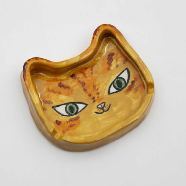 A handmade ceramic orange cat ashtray, featuring a charming design with a realistic orange cat shape, perfect for holding ash and cigarettes. Ένα χειροποίητο κεραμικό τασάκι γάτας πορτοκαλί, με ένα γοητευτικό σχέδιο σε ρεαλιστικό σχήμα πορτοκαλί γάτας, ιδανικό για την αποθήκευση στάχτης και τσιγάρων.