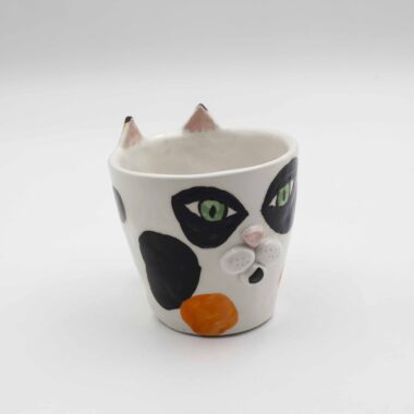 A handmade ceramic calico cat mug, featuring a tri-color cat design with orange, black, and white patches, perfect for enjoying your favorite beverages. Ένα χειροποίητο κεραμικό κούπα γάτας κάλικο, με σχέδιο τριχρωμίας γάτας με πορτοκαλί, μαύρες και λευκές περιοχές, ιδανικό για την απόλαυση των αγαπημένων σας ποτών.