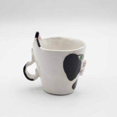 Close-up of a ceramic handmade cat tuxedo mug, featuring a black and white tuxedo cat design on a white mug. Κοντινή λήψη μιας κεραμικής κούπας με μοτίβο γάτας σε τουξέδο, με μαύρο και λευκό σχέδιο γάτας σε ένα λευκό κύπελλο