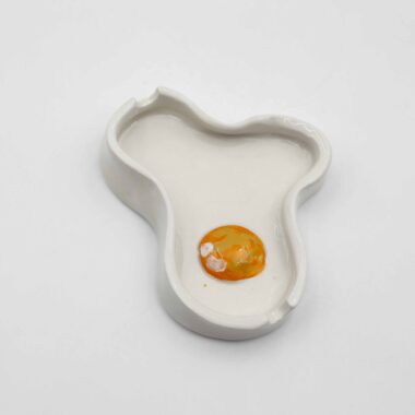 A handmade ceramic egg-shaped ashtray, designed with a smooth surface and a hollow center, perfect for holding ash and cigarettes. Ένα χειροποίητο κεραμικό τασάκι σε σχήμα αυγού, σχεδιασμένο με λεία επιφάνεια και άδειο κέντρο, ιδανικό για την αποθήκευση στάχτης και τσιγάρων.