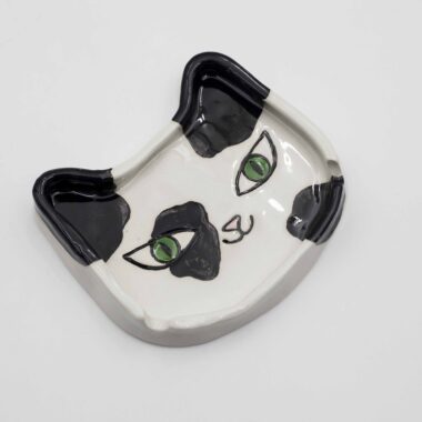 A handmade ceramic tuxedo cat ashtray, featuring a black and white cat design with intricate detailing, perfect for holding ash and cigarettes. Ένα χειροποίητο κεραμικό τασάκι γάτας με σχέδιο μαύρης και λευκής γάτας με λεπτομερείς λεπτομέρειες, ιδανικό για την αποθήκευση στάχτης και τσιγάρων.