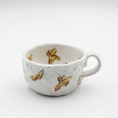 Close-up of a ceramic handmade mug with banana motifs . Κοντινή λήψη μιας χειροποίητης κεραμικής κούπας με μοτίβα μπανανών.