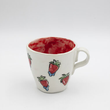 Μια χειροποίητη κεραμική κούπα με φράουλες που έχουν πασπαλιστεί με νερό. A handmade ceramic mug with water-drenched strawberries on it.