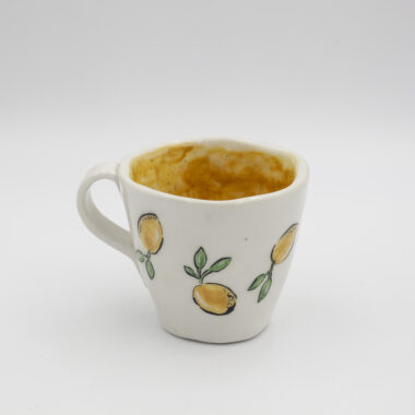 Μια χειροποίητη κεραμική κούπα με λεμόνια. A handmade ceramic mug with water-drenched lemons.