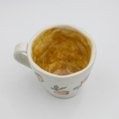 Μια χειροποίητη κεραμική κούπα με λεμόνια. A handmade ceramic mug with water-drenched lemons.