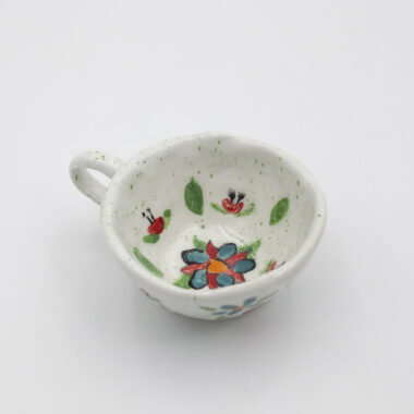 Μια χειροποίητη κεραμική κούπα με λουλούδια. A handmade ceramic cup with flowers.
