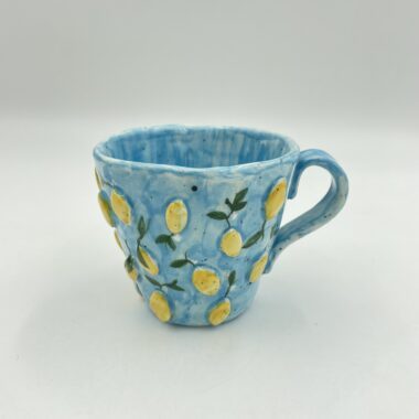 Handmade ceramic mug featuring 3D lemons, perfect for enjoying your favorite beverage. This unique mug combines artisanal craftsmanship with a vibrant, fruity design, making it an ideal gift for lemon lovers and collectors. Χειροποίητη κεραμική κούπα με 3D λεμόνια, ιδανική για να απολαμβάνετε το αγαπημένο σας ρόφημα. Αυτή η μοναδική κούπα συνδυάζει την τεχνογνωσία της χειροποίητης τέχνης με ένα ζωντανό, φρουτώδες σχέδιο, κάνοντάς την ιδανικό δώρο για τους λάτρεις των λεμονιών και συλλέκτες.