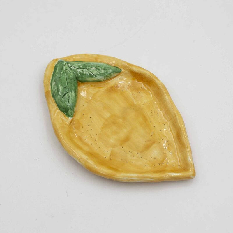 Handmade ceramic lemon plate for jewelry, perfect for adding a touch of Mediterranean charm to your dressing table. This artisanal plate features a vibrant lemon design with intricate details, ideal for organizing and displaying your favorite jewelry pieces. Stylish and functional, this lemon-themed jewelry plate makes a delightful addition to any home decor. Χειροποίητο κεραμικό πιάτο για κοσμήματα με σχέδιο λεμονιού, ιδανικό για να προσθέσετε μια πινελιά μεσογειακής γοητείας στο μπουντουάρ σας. Αυτό το καλλιτεχνικό πιάτο διαθέτει ζωντανό σχέδιο λεμονιού με περίτεχνες λεπτομέρειες, ιδανικό για την οργάνωση και την προβολή των αγαπημένων σας κοσμημάτων. Κομψό και λειτουργικό, αυτό το πιάτο για κοσμήματα με θέμα το λεμόνι αποτελεί μια υπέροχη προσθήκη σε κάθε διακόσμηση σπιτιού.