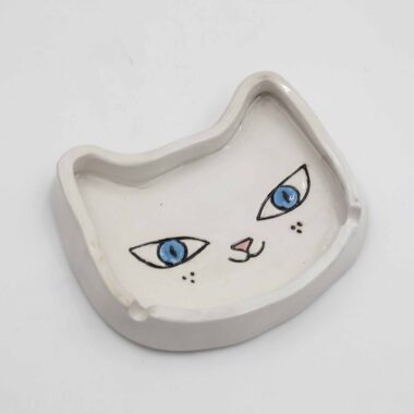 A handmade ceramic tuxedo cat ashtray, featuring a white and white cat design with intricate detailing, perfect for holding ash and cigarettes. Ένα χειροποίητο κεραμικό τασάκι γάτας με σχέδιο λευκής γάτας με λεπτομερείς λεπτομέρειες, ιδανικό για την αποθήκευση στάχτης και τσιγάρων.