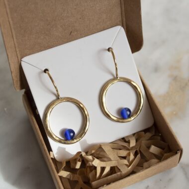 Handmade brass Phaidra circle earrings featuring beautiful blue cat eye stones, crafted by Sunny Designs. These elegant and stylish earrings are perfect for adding a touch of sophistication to any outfit and make a wonderful gift for women. Phaidra earrings, circle earrings, blue cat eye earrings, handmade brass jewelry, Sunny Designs earrings, unique gift, stylish earrings, women’s jewelry, artisan earrings, elegant earrings Χειροποίητα σκουλαρίκια Phaidra σε σχήμα κύκλου από μπρούντζο με όμορφες μπλε πέτρες ματιού της γάτας, φτιαγμένα από τη Sunny Designs. Αυτά τα κομψά και στιλάτα σκουλαρίκια είναι ιδανικά για να προσθέσουν μια αίσθηση κομψότητας σε κάθε ντύσιμο και αποτελούν μια υπέροχη επιλογή δώρου για γυναίκες. σκουλαρίκια Phaidra, κυκλικά σκουλαρίκια, σκουλαρίκια με μπλε μάτι γάτας, χειροποίητο κόσμημα από μπρούντζο, σκουλαρίκια Sunny Designs, μοναδικό δώρο, κομψά σκουλαρίκια, γυναικείο κόσμημα, κοσμήματα τέχνης, κομψά σκουλαρίκια