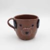 Handmade ceramic dog mug featuring a playful design, crafted from natural red clay and finished with a transparent glaze that highlights the earthy tones. This unique mug, with its charming dog motif, is perfect for dog lovers and adds a fun, artisanal touch to your everyday coffee or tea routine. The combination of the red clay and clear glaze gives it a rustic, handcrafted appeal. Χειροποίητη κεραμική κούπα με σχέδιο σκύλου, κατασκευασμένη από φυσικό κόκκινο πηλό και καλυμμένη με διάφανο γυαλί που αναδεικνύει τους γήινους τόνους. Αυτή η μοναδική κούπα, με το χαριτωμένο μοτίβο σκύλου, είναι ιδανική για λάτρεις των σκύλων και προσθέτει μια διασκεδαστική, καλλιτεχνική πινελιά στην καθημερινή σας ρουτίνα καφέ ή τσαγιού. Ο συνδυασμός του κόκκινου πηλού και του διάφανου γυαλιού της δίνει μια ρουστίκ, χειροποίητη αίσθηση.