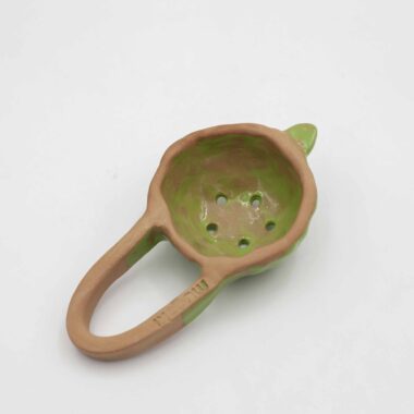 Handmade ceramic tea colander, crafted from natural clay with a smooth, glazed finish. This artisanal tea strainer is designed to easily filter loose leaf tea, offering a stylish and eco-friendly alternative to traditional metal strainers. Its unique, handcrafted design adds a rustic touch to your tea-making ritual, making it a perfect accessory for tea enthusiasts who appreciate handmade ceramics. Χειροποίητο κεραμικό σουρωτήρι για τσάι, κατασκευασμένο από φυσικό πηλό με λείο, γυαλισμένο φινίρισμα. Αυτό το καλλιτεχνικό σουρωτήρι τσαγιού είναι σχεδιασμένο για να φιλτράρει εύκολα το τσάι χύμα, προσφέροντας μια κομψή και φιλική προς το περιβάλλον εναλλακτική λύση στα παραδοσιακά μεταλλικά σουρωτήρια. Ο μοναδικός, χειροποίητος σχεδιασμός του προσθέτει μια ρουστίκ πινελιά στη διαδικασία παρασκευής τσαγιού, ιδανικό για λάτρεις του τσαγιού που εκτιμούν τα χειροποίητα κεραμικά.