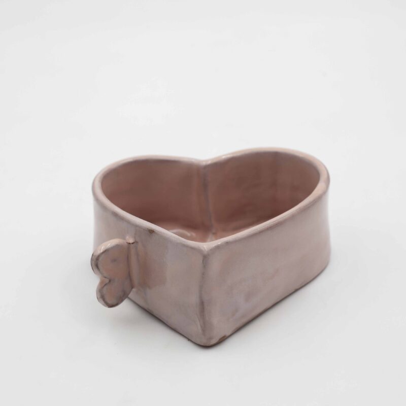 Handmade ceramic heart mug, crafted from natural clay and designed in the shape of a heart. This festive mug is perfect for autumn adding a whimsical and rustic touch to your favorite seasonal beverages. With its pink tone and handcrafted details, the mug combines functionality and charm, making it a cozy addition to any fall-inspired kitchenware collection Χειροποίητη κεραμική κούπα σε σχήμα καρδιάς , κατασκευασμένη από φυσικό πηλό. Αυτή η κούπα είναι ιδανική για το φθινόπωρο, προσθέτοντας μια παιχνιδιάρικη και ρουστίκ πινελιά στα αγαπημένα σας εποχιακά ροφήματα. Σε ροζ τόνους και χειροποίητες λεπτομέρειες, η κούπα συνδυάζει λειτουργικότητα και γοητεία, καθιστώντας την μια ζεστή προσθήκη σε κάθε φθινοπωρινή συλλογή κουζινικών.