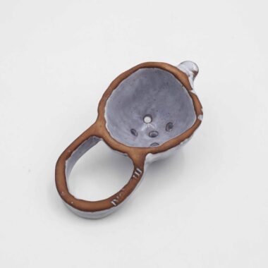 Handmade ceramic tea colander, crafted from natural clay with a smooth, glazed finish. This artisanal tea strainer is designed to easily filter loose leaf tea, offering a stylish and eco-friendly alternative to traditional metal strainers. Its unique, handcrafted design adds a rustic touch to your tea-making ritual, making it a perfect accessory for tea enthusiasts who appreciate handmade ceramics. Χειροποίητο κεραμικό σουρωτήρι για τσάι, κατασκευασμένο από φυσικό πηλό με λείο, γυαλισμένο φινίρισμα. Αυτό το καλλιτεχνικό σουρωτήρι τσαγιού είναι σχεδιασμένο για να φιλτράρει εύκολα το τσάι χύμα, προσφέροντας μια κομψή και φιλική προς το περιβάλλον εναλλακτική λύση στα παραδοσιακά μεταλλικά σουρωτήρια. Ο μοναδικός, χειροποίητος σχεδιασμός του προσθέτει μια ρουστίκ πινελιά στη διαδικασία παρασκευής τσαγιού, ιδανικό για λάτρεις του τσαγιού που εκτιμούν τα χειροποίητα κεραμικά.