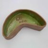 Handmade ceramic boomerang-shaped plate with a unique pink and green glass inscription at the bottom, crafted from red clay. This artistic dish combines a vibrant color palette and organic design, ideal for adding a touch of elegance and originality to any home decor. Χειροποίητο κεραμικό πιάτο σε σχήμα μπούμερανγκ με μοναδική ροζ και πράσινη υάλωση στον πάτο, φτιαγμένο από κόκκινο πηλό. Αυτό το καλλιτεχνικό πιάτο συνδυάζει ζωντανά χρώματα και οργανικό σχέδιο, ιδανικό για να προσθέσει κομψότητα και πρωτοτυπία σε κάθε διακόσμηση σπιτιού.