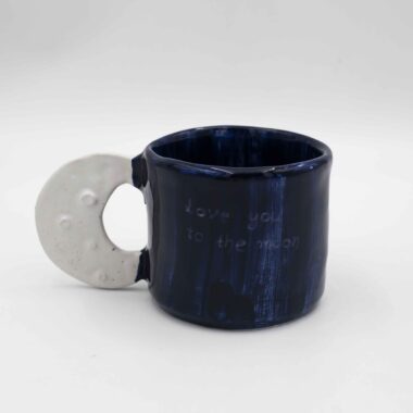 Handmade ceramic blue mug with a unique crescent moon handle, perfect for coffee or tea lovers seeking an artistic, celestial-inspired touch to their drinkware collection. Χειροποίητη κεραμική μπλε κούπα με ιδιαίτερο χερούλι σε σχήμα μισοφέγγαρου, ιδανική για λάτρεις του καφέ ή τσαγιού που αναζητούν μια καλλιτεχνική, αστρική πινελιά στη συλλογή τους.