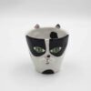 Handmade ceramic mug with a cat face design, available in calico, tuxedo, white, and orange cat variations. Perfect for cat lovers looking to add a cute, personalized touch to their drinkware collection." Greek: "Χειροποίητη κεραμική κούπα με σχέδιο προσώπου γάτας, διαθέσιμη σε εκδόσεις τρίχρωμης, δίχρωμης, λευκής και πορτοκαλί γάτας. Ιδανική για φιλόζωους που θέλουν να προσθέσουν μια χαριτωμένη, προσωπική πινελιά στη συλλογή τους από κούπες.