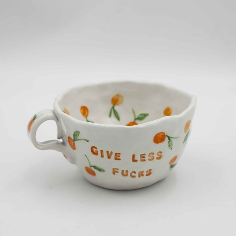 Unique, handmade ceramic mug featuring the inspiring phrase "Give Less Fucks and Fruits," perfect for adding a touch of humor and motivation to your daily routine. Handcrafted ceramic mug with a witty and eye-catching design, ideal for coffee, tea, or any other beverage. Eco-friendly, artisan ceramic mug with a bold statement, making it a great gift for friends, family, or yourself. Μοναδικό, χειροποίητο κεραμικό φλιτζάνι με την εμπνευσμένη φράση "Δώσε λιγότερα κατάρες και περισσότερα φρούτα", ιδανικό για να προσθέσετε μια δόση χιούμορ και κινήτρου στην καθημερινότητά σας. Χειροποίητο κεραμικό φλιτζάνι με μια ευφάνταστη και εντυπωσιακή σχεδίαση, ιδανικό για καφέ, τσάι ή οποιοδήποτε άλλο ρόφημα. Φιλικό προς το περιβάλλον, αριστοτεχνικό κεραμικό φλιτζάνι με μια τολμηρή δήλωση, καθιστώντας το ένα εξαιρετικό δώρο για φίλους, οικογένεια ή τον εαυτό σας.