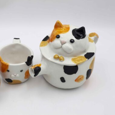 Adorable ceramic tea set featuring two cups calico cats, perfect for tea lovers and cat enthusiasts. A unique and heartwarming addition to any kitchen. Αγαπημένο σετ τσαγιού από κεραμικό με δύο φλιτζάνια γατάκια καλικό, ιδανικό για λάτρεις του τσαγιού και των γατών. Μια μοναδική και ζεστή προσθήκη σε κάθε κουζίνα.