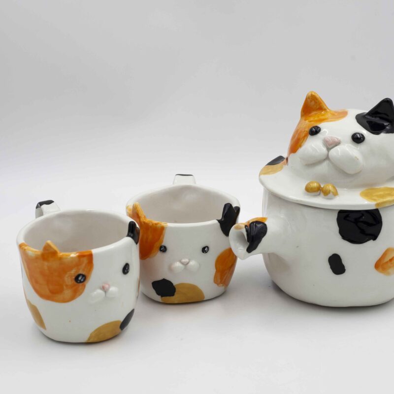 Adorable ceramic tea set featuring two cups calico cats, perfect for tea lovers and cat enthusiasts. A unique and heartwarming addition to any kitchen. Αγαπημένο σετ τσαγιού από κεραμικό με δύο φλιτζάνια γατάκια καλικό, ιδανικό για λάτρεις του τσαγιού και των γατών. Μια μοναδική και ζεστή προσθήκη σε κάθε κουζίνα.