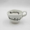 Elegant white ceramic mug with a handwritten inspirational message, perfect for daily motivation and mindfulness. Κομψό λευκό κεραμικό φλιτζάνι με χειρόγραφο εμπνευστικό μήνυμα, ιδανικό για καθημερινή κινητοποίηση και ενσυνειδητότητα.