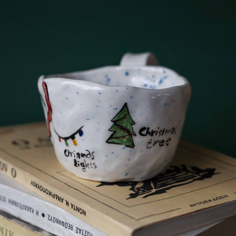 Beautiful handmade ceramic Christmas mugs featuring festive designs like gingerbread cookies and Christmas trees, perfect for cozy winter mornings. Artisan-crafted with care, ideal for gifting or enjoying hot cocoa. Unique holiday mugs made with love. "Όμορφες χειροποίητες κεραμικές κούπες για τα Χριστούγεννα, με γιορτινά σχέδια όπως μπισκότα τζίντζερμαν και χριστουγεννιάτικα δέντρα. Ιδανικές για ζεστά πρωινά του χειμώνα. Δημιουργημένες με μεράκι, τέλειες για δώρα ή για απολαυστική ζεστή σοκολάτα. Μοναδικές εορταστικές κούπες φτιαγμένες με αγάπη