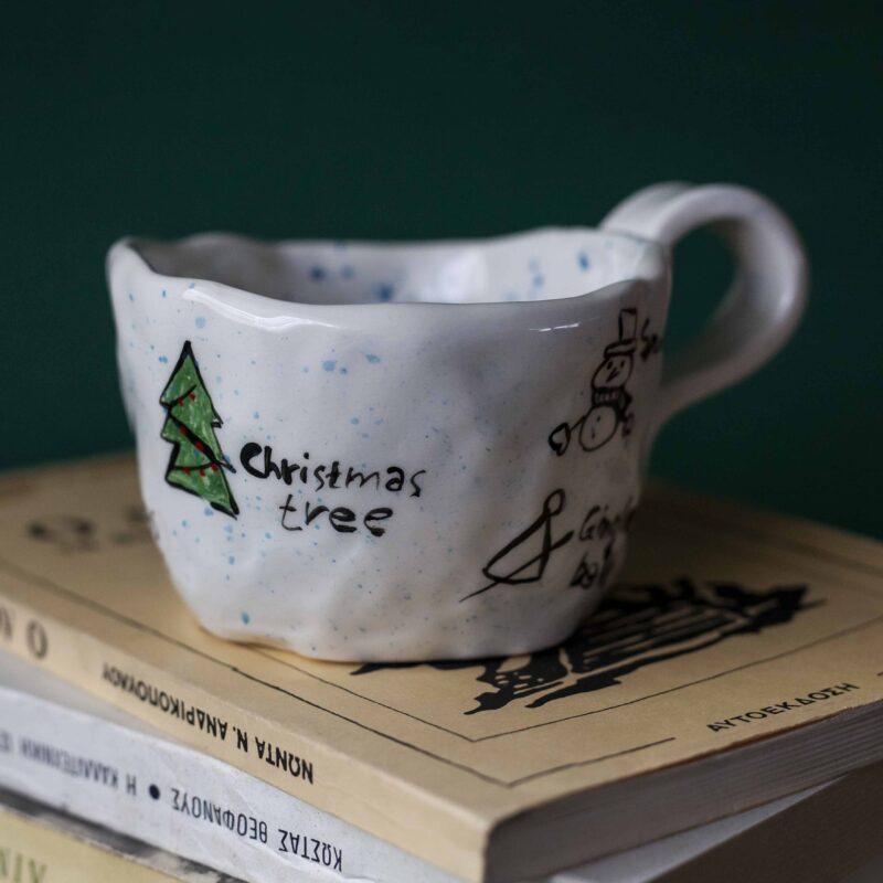 Beautiful handmade ceramic Christmas mugs featuring festive designs like gingerbread cookies and Christmas trees, perfect for cozy winter mornings. Artisan-crafted with care, ideal for gifting or enjoying hot cocoa. Unique holiday mugs made with love. "Όμορφες χειροποίητες κεραμικές κούπες για τα Χριστούγεννα, με γιορτινά σχέδια όπως μπισκότα τζίντζερμαν και χριστουγεννιάτικα δέντρα. Ιδανικές για ζεστά πρωινά του χειμώνα. Δημιουργημένες με μεράκι, τέλειες για δώρα ή για απολαυστική ζεστή σοκολάτα. Μοναδικές εορταστικές κούπες φτιαγμένες με αγάπη