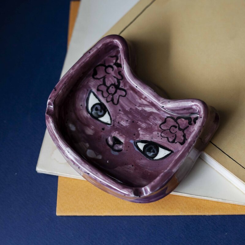 A handmade ceramic tuxedo cat ashtray, featuring a white and white cat design with intricate detailing, perfect for holding ash and cigarettes. Ένα χειροποίητο κεραμικό τασάκι γάτας με σχέδιο λευκής γάτας με λεπτομερείς λεπτομέρειες, ιδανικό για την αποθήκευση στάχτης και τσιγάρων.