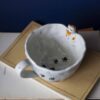 Large handmade ceramic mugs featuring adorable 3D cats climbing on the sides, perfect for cat lovers and tea or coffee enthusiasts. Unique artisan-crafted design combining functionality with playful charm. Ideal as a gift or for adding a whimsical touch to your daily routine. Μεγάλες χειροποίητες κεραμικές κούπες με χαριτωμένες τρισδιάστατες γάτες που σκαρφαλώνουν στις πλευρές τους. Ιδανικές για λάτρεις των γατών και του καφέ ή του τσαγιού. Μοναδικός καλλιτεχνικός σχεδιασμός που συνδυάζει λειτουργικότητα με παιχνιδιάρικη γοητεία. Τέλειες για δώρα ή για να προσθέσετε μια χαρούμενη πινελιά στην καθημερινότητά σας.