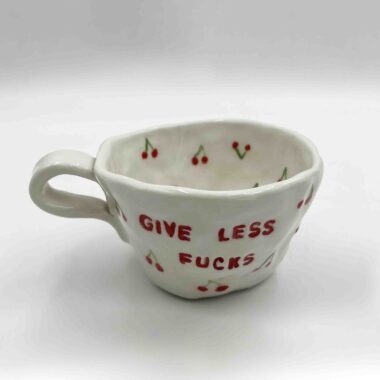 Handmade ceramic mugs adorned with playful fruit designs and the bold message 'Give Less Fucks' on the front. Perfect for adding a touch of humor and personality to your daily coffee or tea!