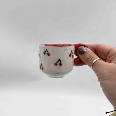 Handmade single espresso cup adorned with a charming cherry design. A delightful choice for coffee lovers who enjoy a touch of sweetness in their style. Χειροποίητο φλιτζάνι εσπρέσο διακοσμημένο με ένα χαριτωμένο σχέδιο κερασιών. Μια απολαυστική επιλογή για τους λάτρεις του καφέ που εκτιμούν μια δόση γλυκύτητας στο στυλ τους.