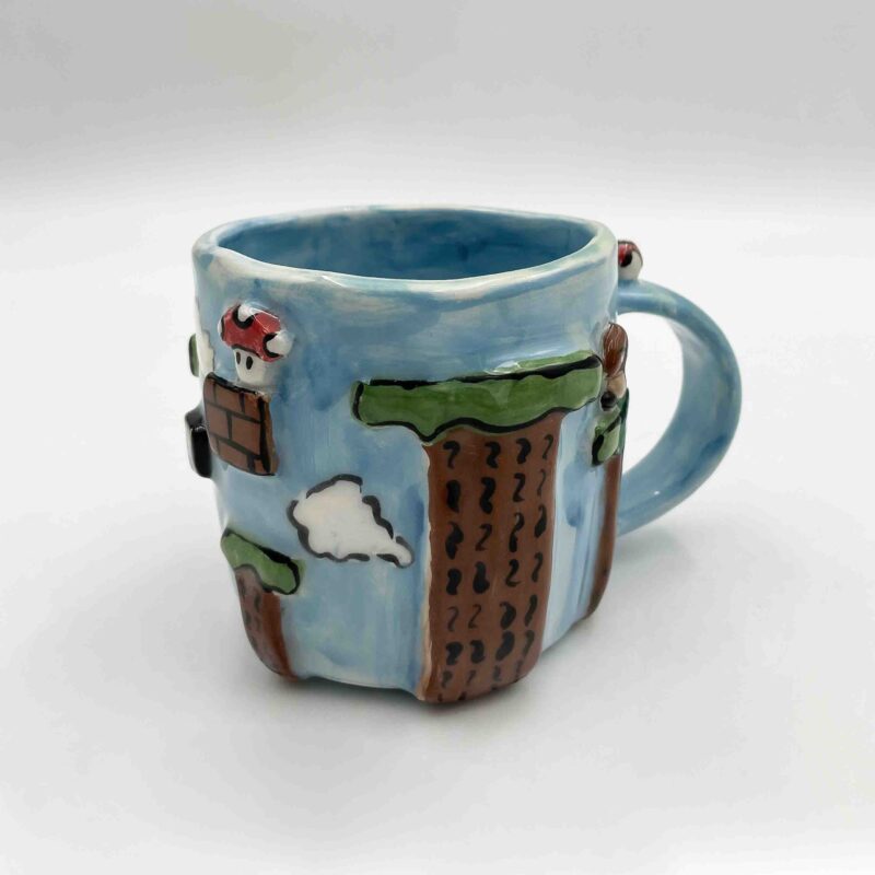 Handcrafted Super Mario-themed pottery collection featuring a 3D mug inspired by the iconic Sky Level, colorful coasters with pixel art designs, and a charming mushroom-shaped ashtray. Perfect for gamers and pottery lovers! Χειροποίητη συλλογή κεραμικών με θέμα τον Super Mario, που περιλαμβάνει μια 3D κούπα εμπνευσμένη από το εμβληματικό Sky Level, πολύχρωμα σουβέρ με pixel art σχέδια και ένα χαριτωμένο τασάκι σε σχήμα μανιταριού. Ιδανικό για gamers και λάτρεις της κεραμικής!