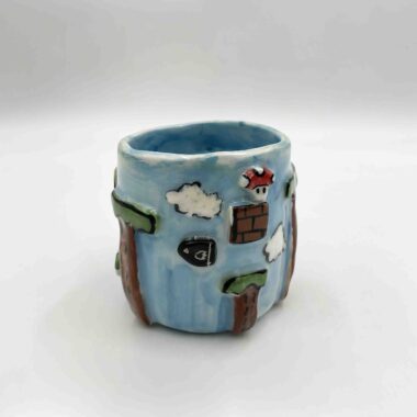 Handcrafted Super Mario-themed pottery collection featuring a 3D mug inspired by the iconic Sky Level, colorful coasters with pixel art designs, and a charming mushroom-shaped ashtray. Perfect for gamers and pottery lovers! Χειροποίητη συλλογή κεραμικών με θέμα τον Super Mario, που περιλαμβάνει μια 3D κούπα εμπνευσμένη από το εμβληματικό Sky Level, πολύχρωμα σουβέρ με pixel art σχέδια και ένα χαριτωμένο τασάκι σε σχήμα μανιταριού. Ιδανικό για gamers και λάτρεις της κεραμικής!