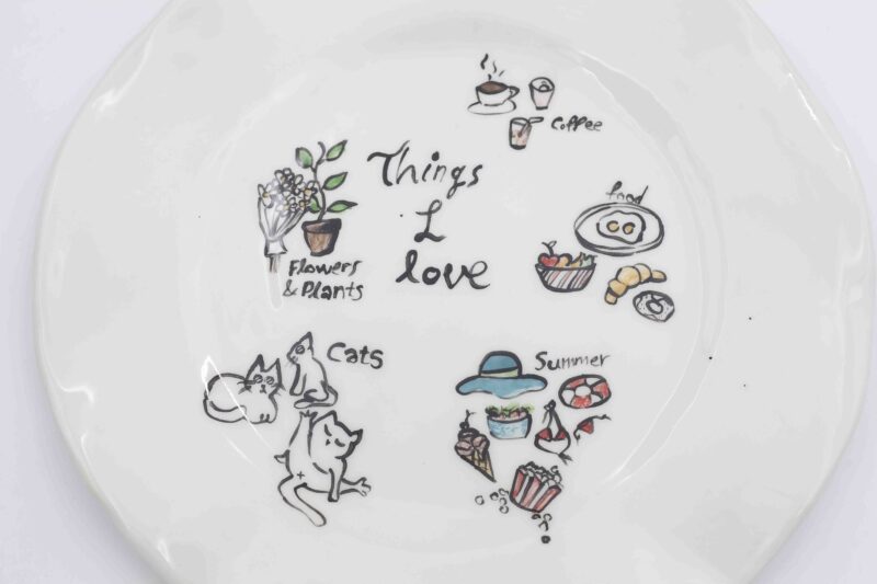 Handmade ceramic plate featuring charming hand-painted designs inspired by favorite things—cats, food, summer, coffee, plants, and flowers. A unique and artistic decorative or serving plate, perfect for adding personality to your table or gifting to a loved one." Greek: "Χειροποίητο κεραμικό πιάτο με χαριτωμένα ζωγραφισμένα σχέδια εμπνευσμένα από αγαπημένα πράγματα—γάτες, φαγητό, καλοκαίρι, καφέ, φυτά και λουλούδια. Ένα μοναδικό και καλλιτεχνικό πιάτο για διακόσμηση ή σερβίρισμα, ιδανικό για να δώσει χαρακτήρα στο τραπέζι σας ή ως ξεχωριστό δώρο.