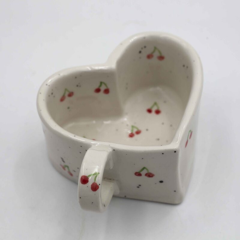 Handmade heart-shaped ceramic mugs, perfect for Valentine's Day and romantic moments. Each mug is decorated with charming hand-painted details, featuring cherries, an array of fruits, delicate flowers, and tiny hearts. A unique and thoughtful gift for loved ones, blending artistic beauty with everyday warmth and love. Χειροποίητες κεραμικές κούπες σε σχήμα καρδιάς, ιδανικές για την Ημέρα του Αγίου Βαλεντίνου και ρομαντικές στιγμές. Κάθε κούπα είναι διακοσμημένη με χαριτωμένες, ζωγραφισμένες στο χέρι λεπτομέρειες, όπως κεράσια, διάφορα φρούτα, λεπτεπίλεπτα λουλούδια και μικρές καρδιές. Ένα μοναδικό και τρυφερό δώρο για τα αγαπημένα σας πρόσωπα, που συνδυάζει την τέχνη με τη ζεστασιά της καθημερινότητας.