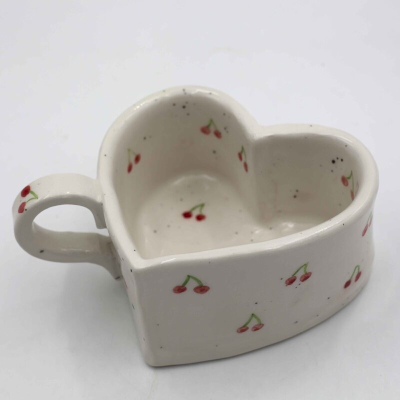 Handmade heart-shaped ceramic mugs, perfect for Valentine's Day and romantic moments. Each mug is decorated with charming hand-painted details, featuring cherries, an array of fruits, delicate flowers, and tiny hearts. A unique and thoughtful gift for loved ones, blending artistic beauty with everyday warmth and love. Χειροποίητες κεραμικές κούπες σε σχήμα καρδιάς, ιδανικές για την Ημέρα του Αγίου Βαλεντίνου και ρομαντικές στιγμές. Κάθε κούπα είναι διακοσμημένη με χαριτωμένες, ζωγραφισμένες στο χέρι λεπτομέρειες, όπως κεράσια, διάφορα φρούτα, λεπτεπίλεπτα λουλούδια και μικρές καρδιές. Ένα μοναδικό και τρυφερό δώρο για τα αγαπημένα σας πρόσωπα, που συνδυάζει την τέχνη με τη ζεστασιά της καθημερινότητας.