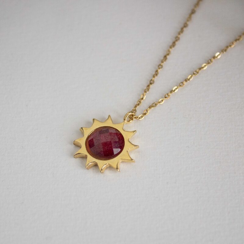Sun necklace with red stone, handmade brass pendant plated in 24k gold on a stainless steel chain. Bold celestial-inspired artisan jewelry with vibrant red gemstone detail, affordable handmade accessory by Sunny Designs small business.Κολιέ Sun με κόκκινη πέτρα, χειροποίητο μενταγιόν από ορείχαλκο επιχρυσωμένο 24 καράτια σε ατσάλινη αλυσίδα. Εντυπωσιακό κόσμημα εμπνευσμένο από τα ουράνια σύμβολα με ζωντανή κόκκινη πέτρα, προσιτό χειροποίητο αξεσουάρ από τη μικρή επιχείρηση Sunny Designs.