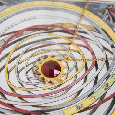 Sun necklace with red stone, handmade brass pendant plated in 24k gold on a stainless steel chain. Bold celestial-inspired artisan jewelry with vibrant red gemstone detail, affordable handmade accessory by Sunny Designs small business.Κολιέ Sun με κόκκινη πέτρα, χειροποίητο μενταγιόν από ορείχαλκο επιχρυσωμένο 24 καράτια σε ατσάλινη αλυσίδα. Εντυπωσιακό κόσμημα εμπνευσμένο από τα ουράνια σύμβολα με ζωντανή κόκκινη πέτρα, προσιτό χειροποίητο αξεσουάρ από τη μικρή επιχείρηση Sunny Designs.