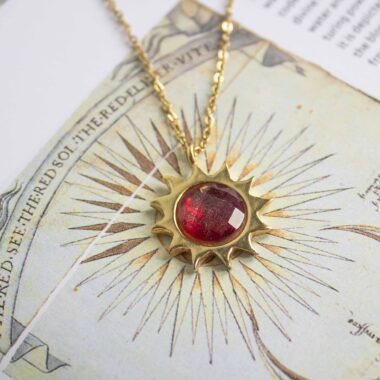 Sun necklace with red stone, handmade brass pendant plated in 24k gold on a stainless steel chain. Bold celestial-inspired artisan jewelry with vibrant red gemstone detail, affordable handmade accessory by Sunny Designs small business.Κολιέ Sun με κόκκινη πέτρα, χειροποίητο μενταγιόν από ορείχαλκο επιχρυσωμένο 24 καράτια σε ατσάλινη αλυσίδα. Εντυπωσιακό κόσμημα εμπνευσμένο από τα ουράνια σύμβολα με ζωντανή κόκκινη πέτρα, προσιτό χειροποίητο αξεσουάρ από τη μικρή επιχείρηση Sunny Designs.