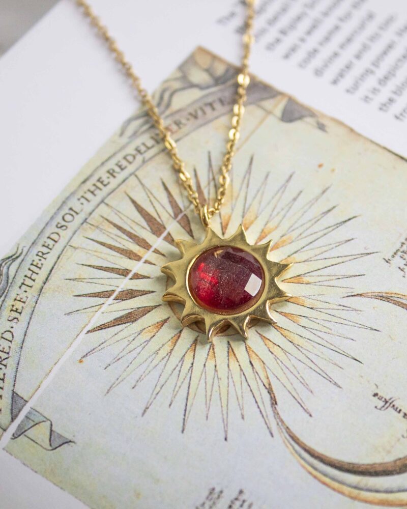 Sun necklace with red stone, handmade brass pendant plated in 24k gold on a stainless steel chain. Bold celestial-inspired artisan jewelry with vibrant red gemstone detail, affordable handmade accessory by Sunny Designs small business.Κολιέ Sun με κόκκινη πέτρα, χειροποίητο μενταγιόν από ορείχαλκο επιχρυσωμένο 24 καράτια σε ατσάλινη αλυσίδα. Εντυπωσιακό κόσμημα εμπνευσμένο από τα ουράνια σύμβολα με ζωντανή κόκκινη πέτρα, προσιτό χειροποίητο αξεσουάρ από τη μικρή επιχείρηση Sunny Designs.