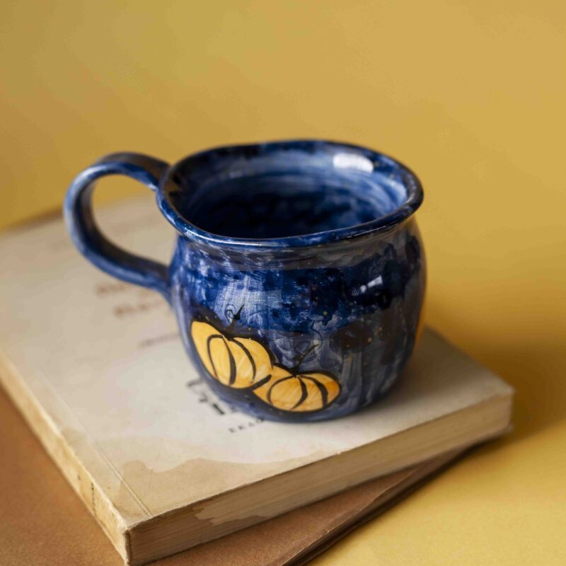 Handmade ceramic blue mug with pumpkins. shaped like a cauldron. For Halloween and fall vibes all the way.