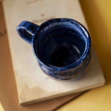 Handmade ceramic blue mug with pumpkins. shaped like a cauldron. For Halloween and fall vibes all the way.